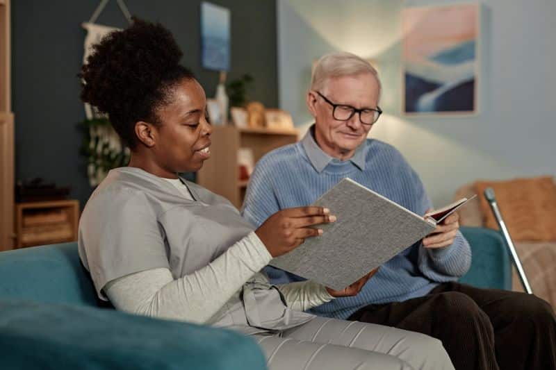 Nurse sitting with patient looking at photo album