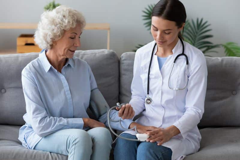 Nurse taking patient's blood pressure on a couch