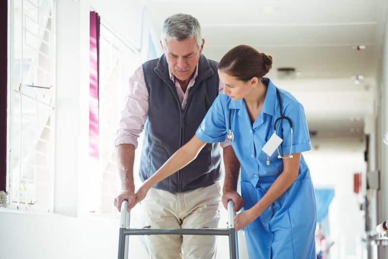 Nurse helping patient use walker after surgery