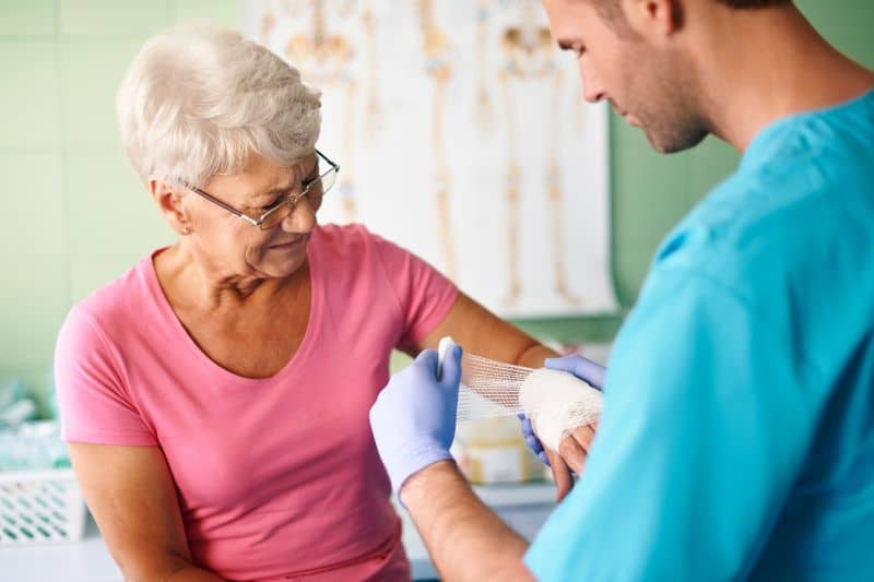 Wound Care Nurse wrapping patient's hand in gauze