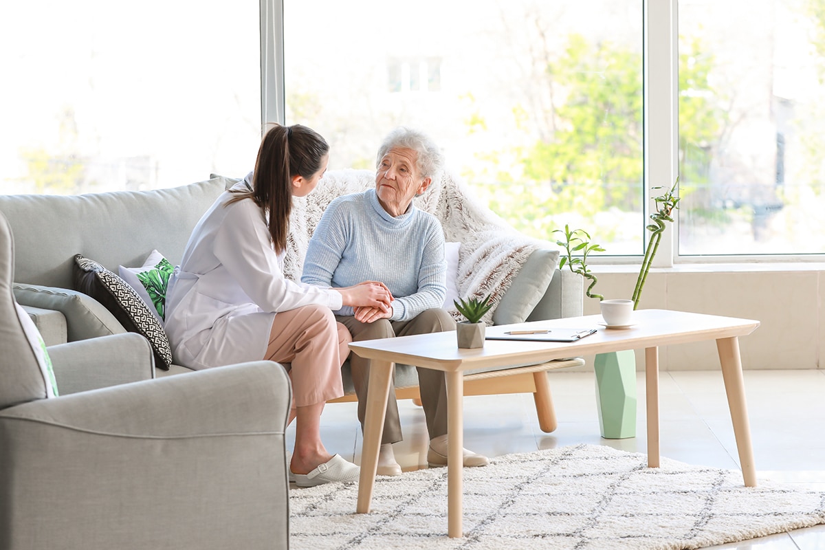Staff member having a conversation with an elderly woman in a comfortable, home-like setting